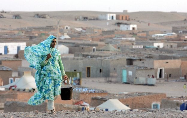 Imagen de archivo en la que aparece una mujer que camina junto a un campo de refugiados en Tinduf. / HOY