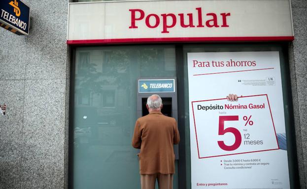Un hombre, en el cajero de una sede del Popular./Andrea Comas (Reuters)