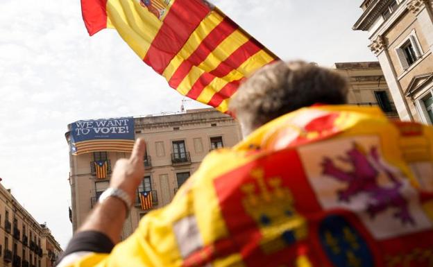 Un manifestante ataviado con una bandera española, ante un cartel a favor del referéndum./Pau Barrena (Afp)