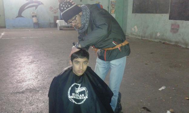 Juan Antonio Galán cortando el cabello a un niño refugiado en Atenas. :: hoy/