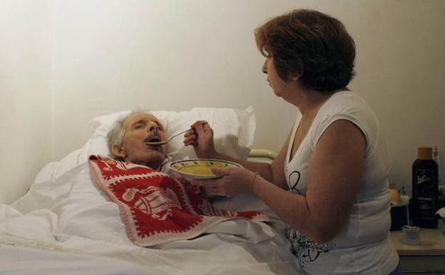 Mujer da de comer a su esposo, enfermo de alzhéimer. /Nacho Doce (Reuters)