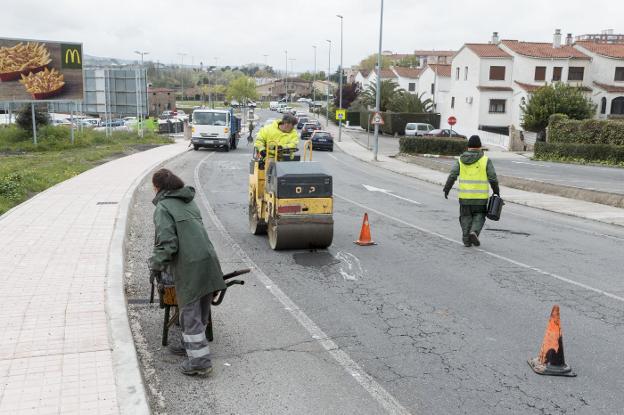 Trabajadores municipales tapando baches la semana pasada en el Camino de las Huertas. :: andy solé/