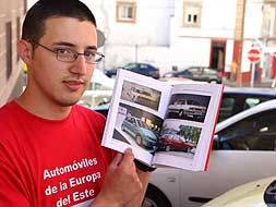 Alfredo Martín muestra algunas de las numerosas fotos de los coches del Este que trae la guía./A.SOLÉ/