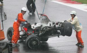 El coche destrozado del piloto español Fernando Alonso (McLaren-Mercedes) es retirado de la pista. / EFE/