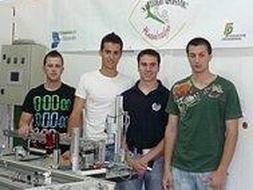 Los cuatro ganadores en el aula junto a una de las máquinas con las que trabajan. / I. V./