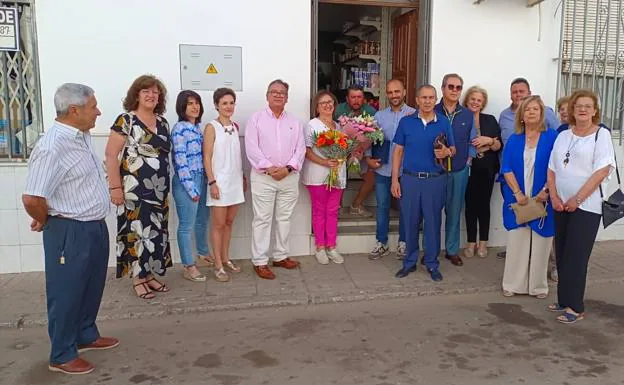 Vecinos, concejales, familiares, amigos y el alcalde posan junto a Ángela en su frutería. 