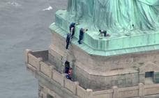 Una manifestante se encarama a la Estatua de la Libertad para confrontar las política de Trump