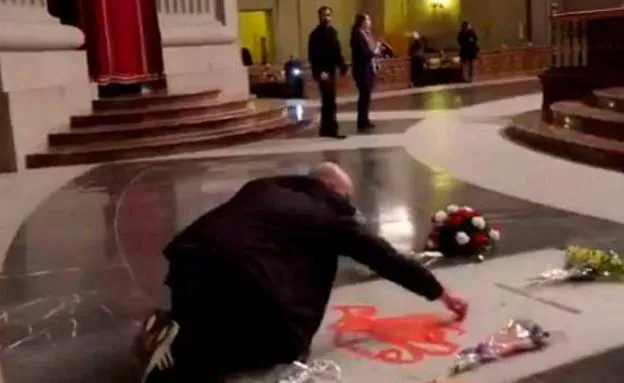 Un hombre pinta de rojo la tumba de Franco