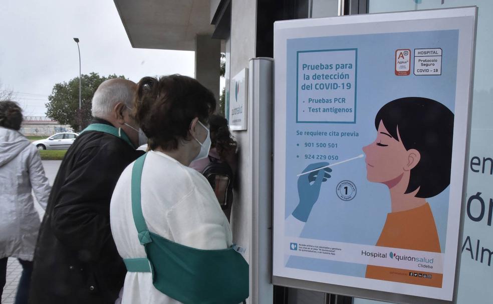 Dos personas mirando el cartel que anuncia las pruebas para la detección de la covid en un centro de Badajoz./Casimiro Moreno