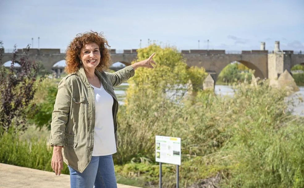 Maribel Paredes, en la margen izquierda, señalando el Puente de Palmas, cuya historia fascina a los turistas que guía. /José Vicente Arnelas