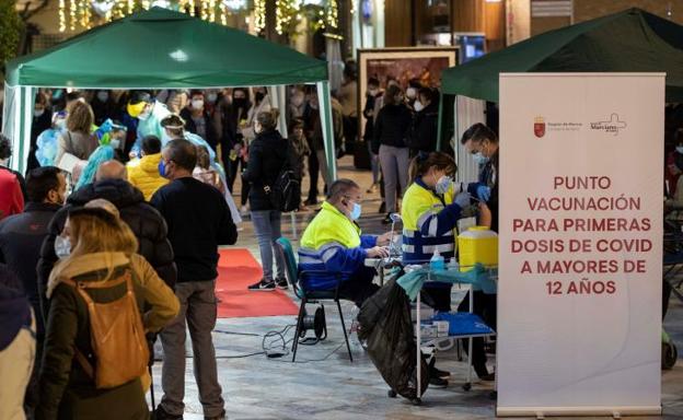 Numerosas personas hacen cola para hacerse un test de antígenos o vacunarse de la primera dosis contra la covid en Murcia./EFE