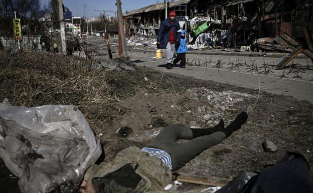 A man and his son pass a dead body in the Ukrainian city of Irpin. 
