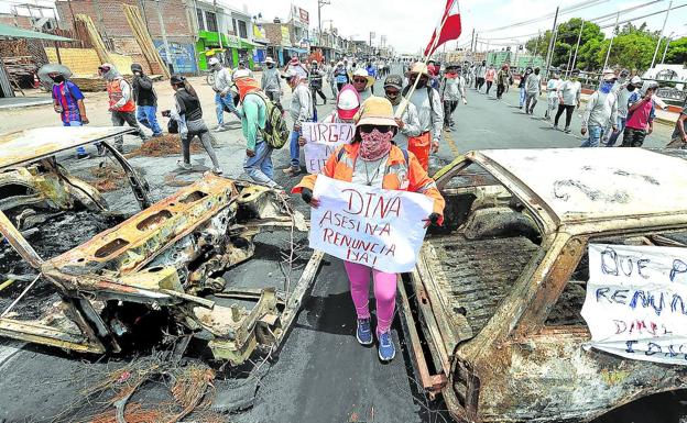 Simpatizantes de Castillo caminan entre dos vehículos incinerados en Arequipa mientras se manifiestan para pedir la salida de Din a Boluarte y el cierre del Congreso./José Sotomayor Jiménez/EFE